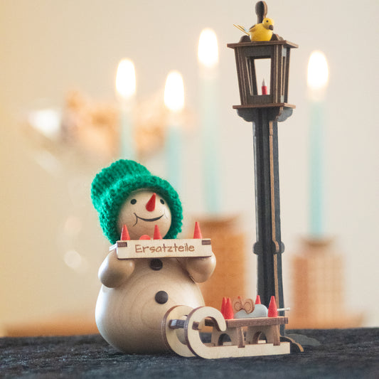 Schneemann mit Bauchladen und Schlitten