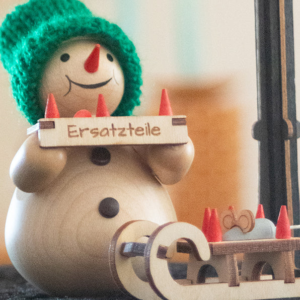 Schneemann mit Bauchladen und Schlitten